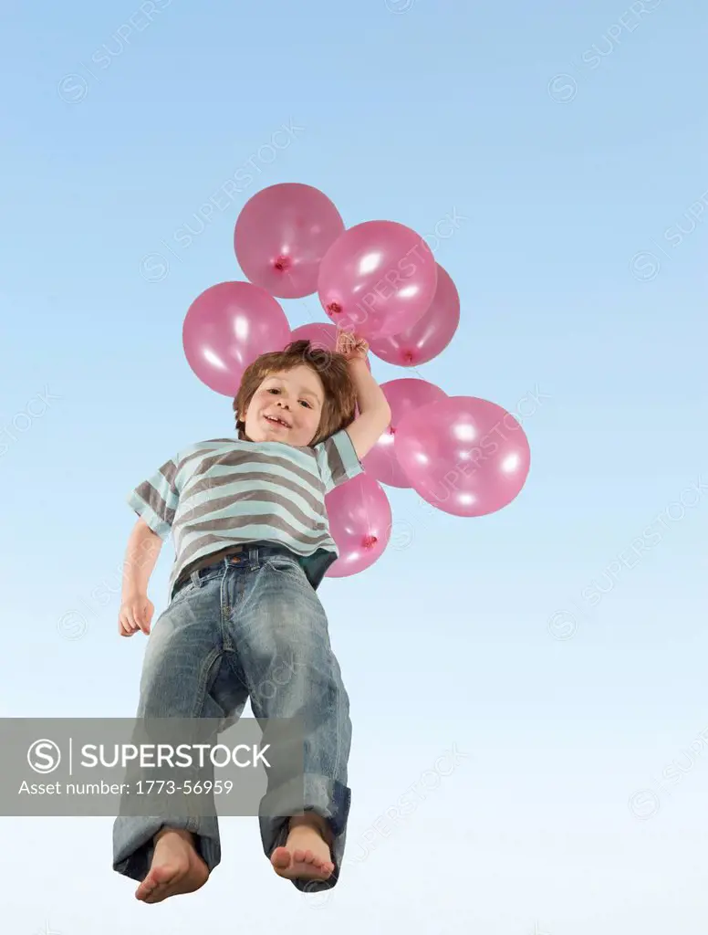 Boy jumping with bunch of balloons