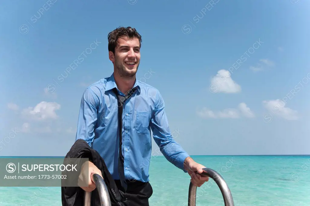 Businessman in wet clothes climbing dock