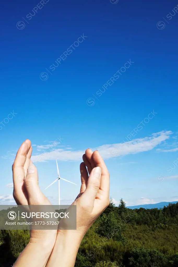 Hands cupped around wind turbine