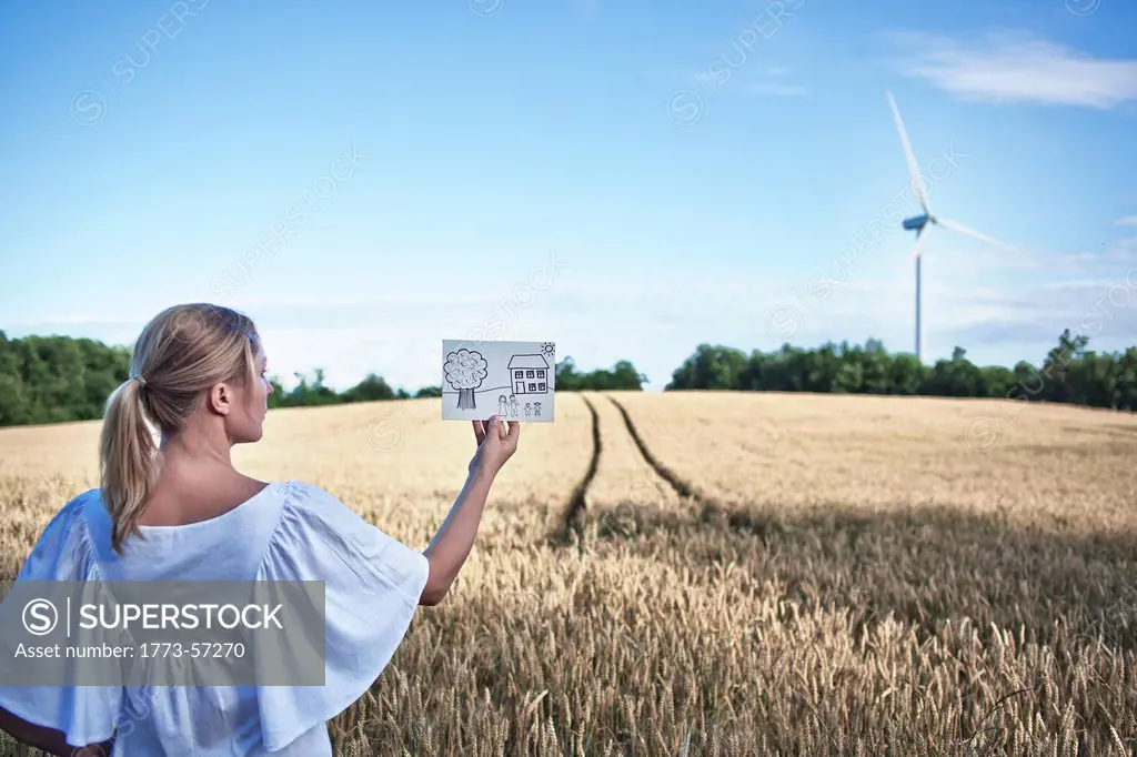 Woman examining childs drawing in field