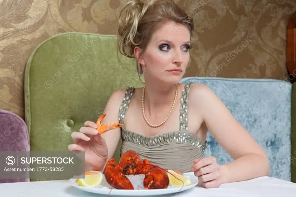 Woman in evening gown eating lobster