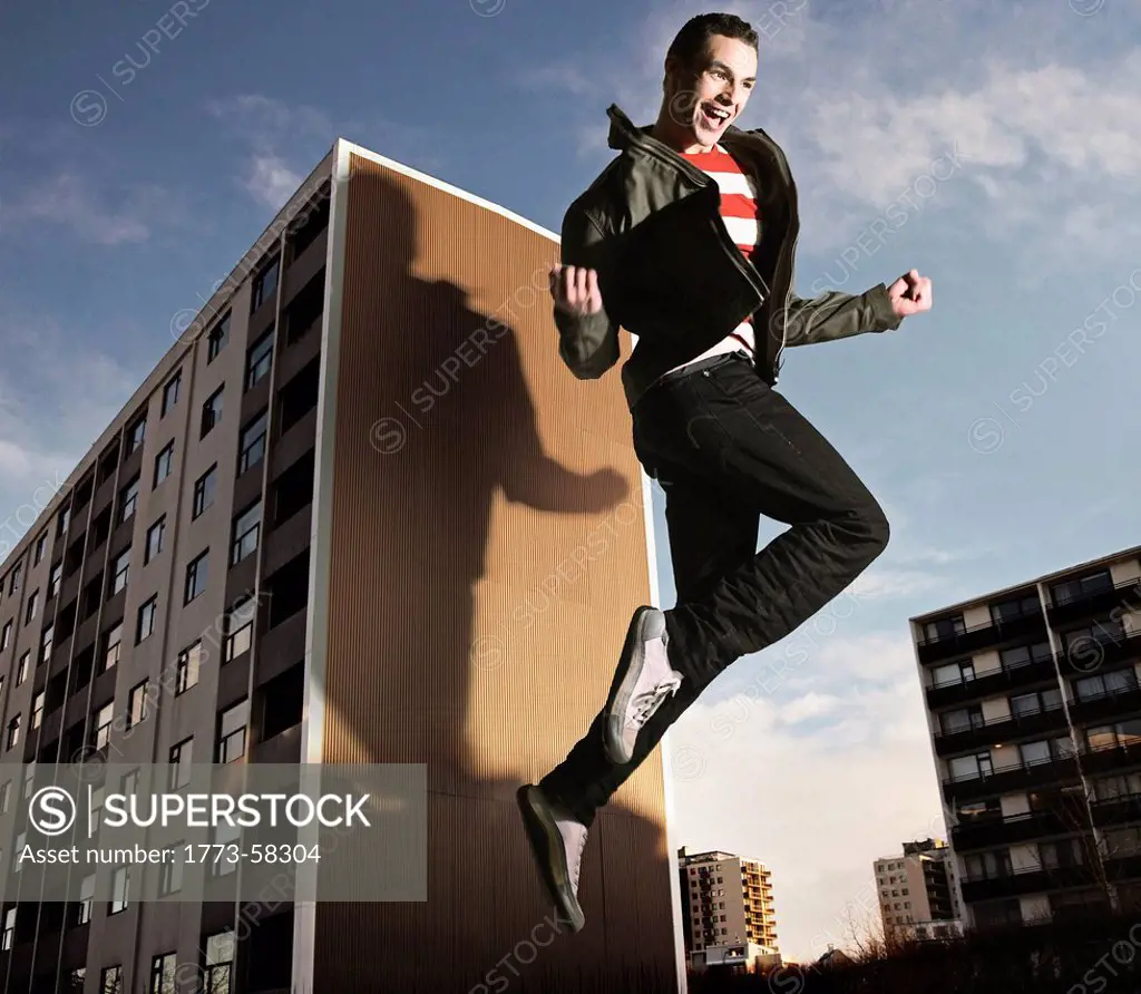 Oversized man jumping by building