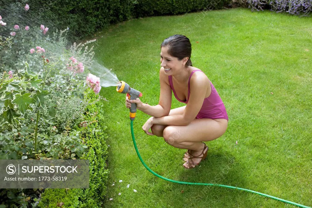 Woman in swimsuit watering plants