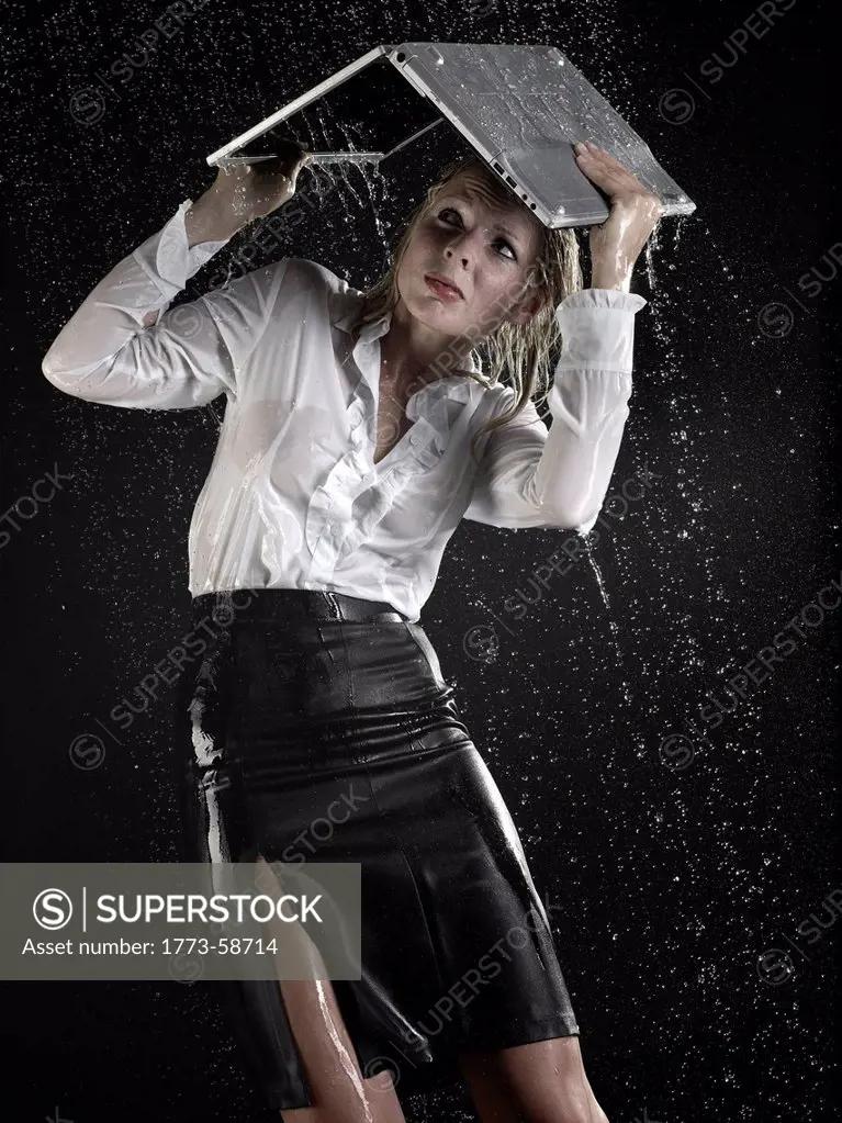 Businesswoman under laptop in rain