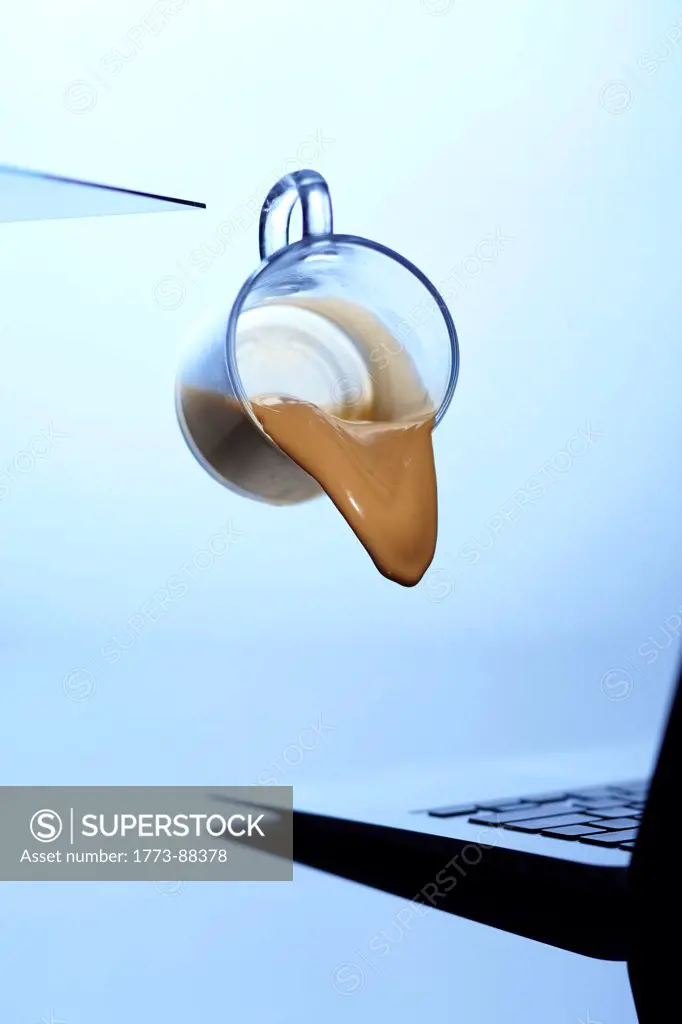 Coffee cup spilling on laptop
