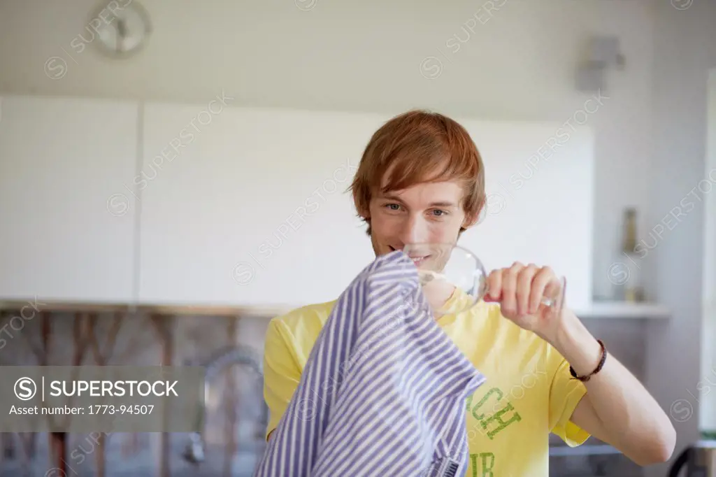 Man polishing wine glass in kitchen