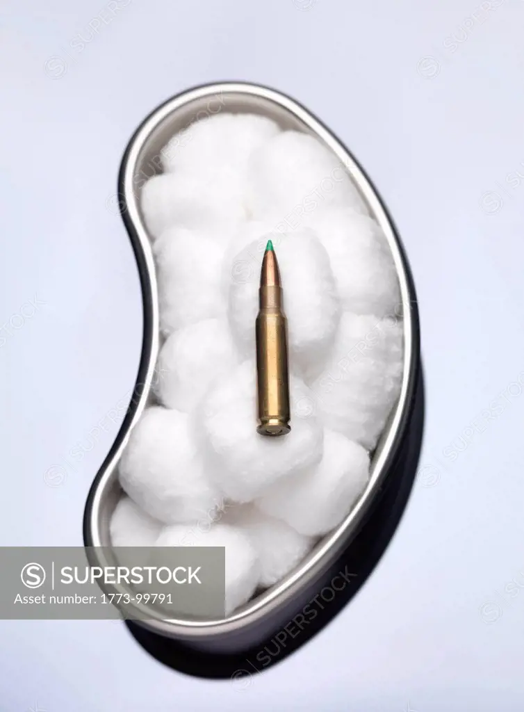 Bullet laying in cotton wool in surgical tray illustrating peace and diplomacy. Danger, bullet,weapons,crime