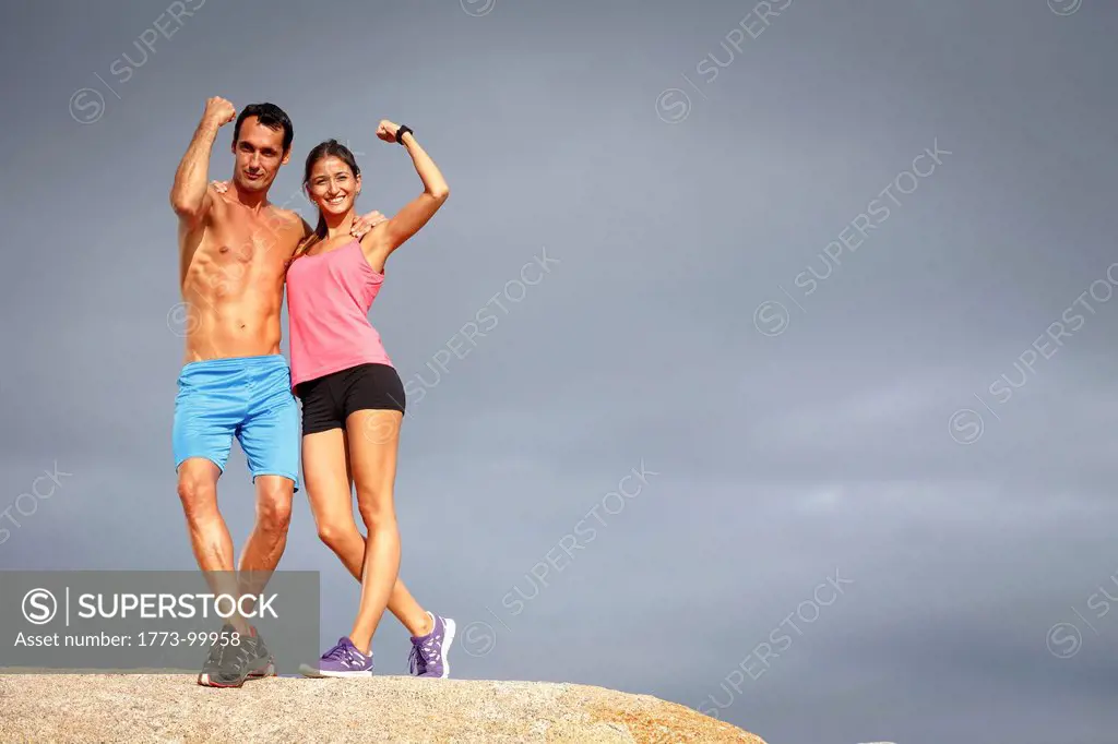 Couple flexing muscles on boulder