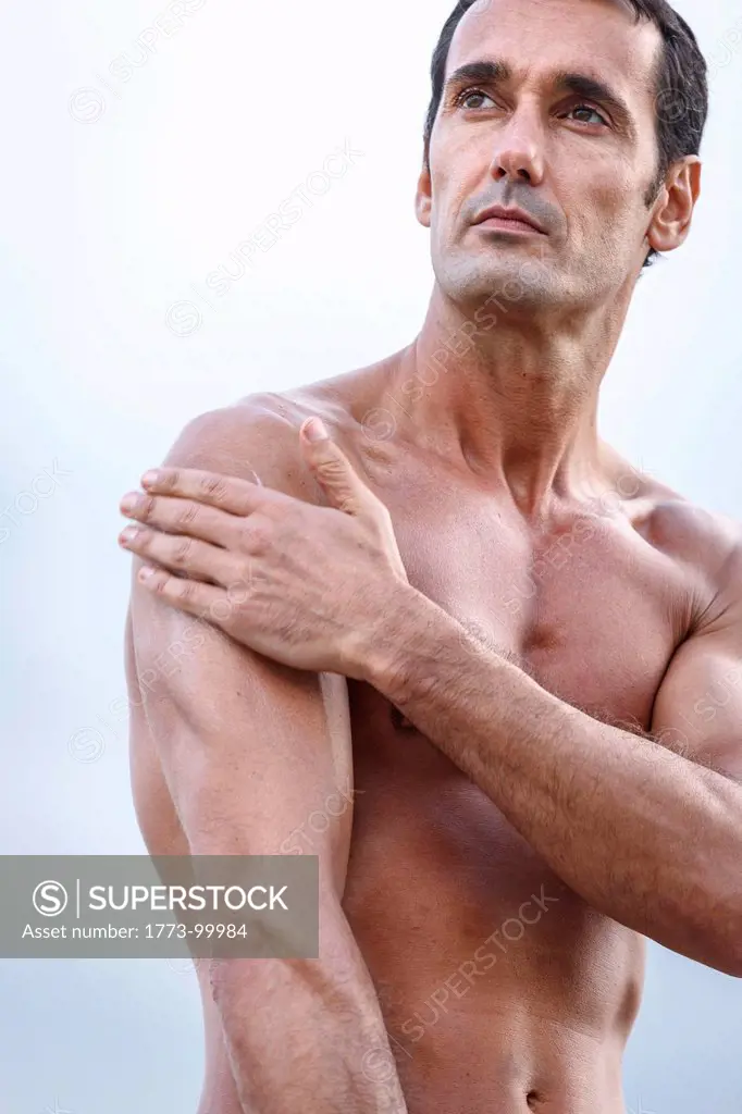 Semi nude man rubbing on sunscreen