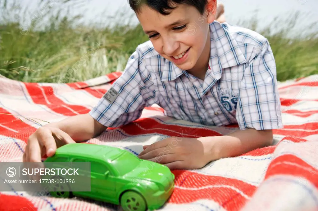 Boy playing with green toy car