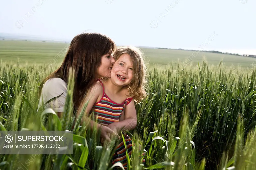 Mother kissing child in wheat field