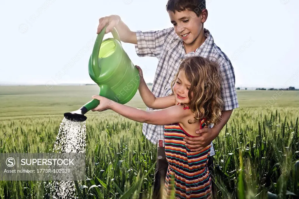 Boy helping girl with watering can
