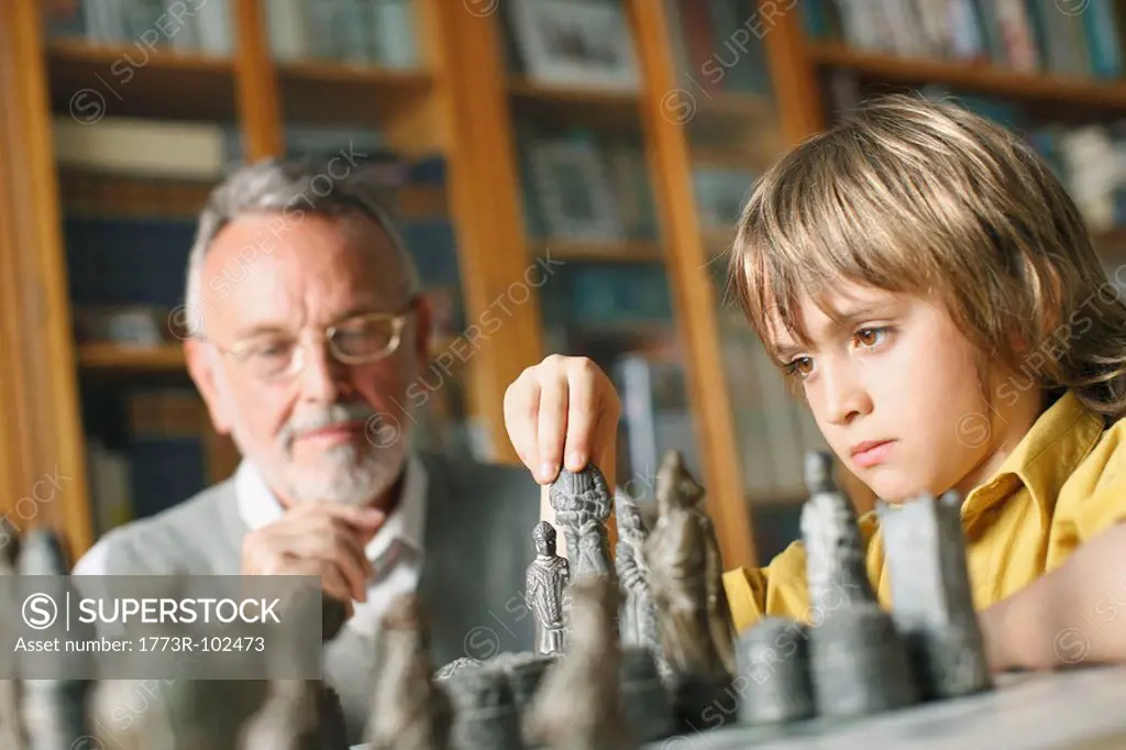 Young boy playing chess with grandfather