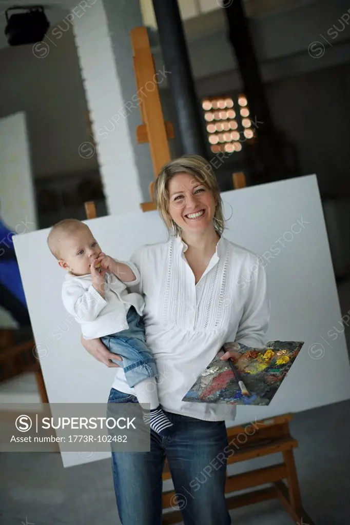 Mother holding baby in front of easel
