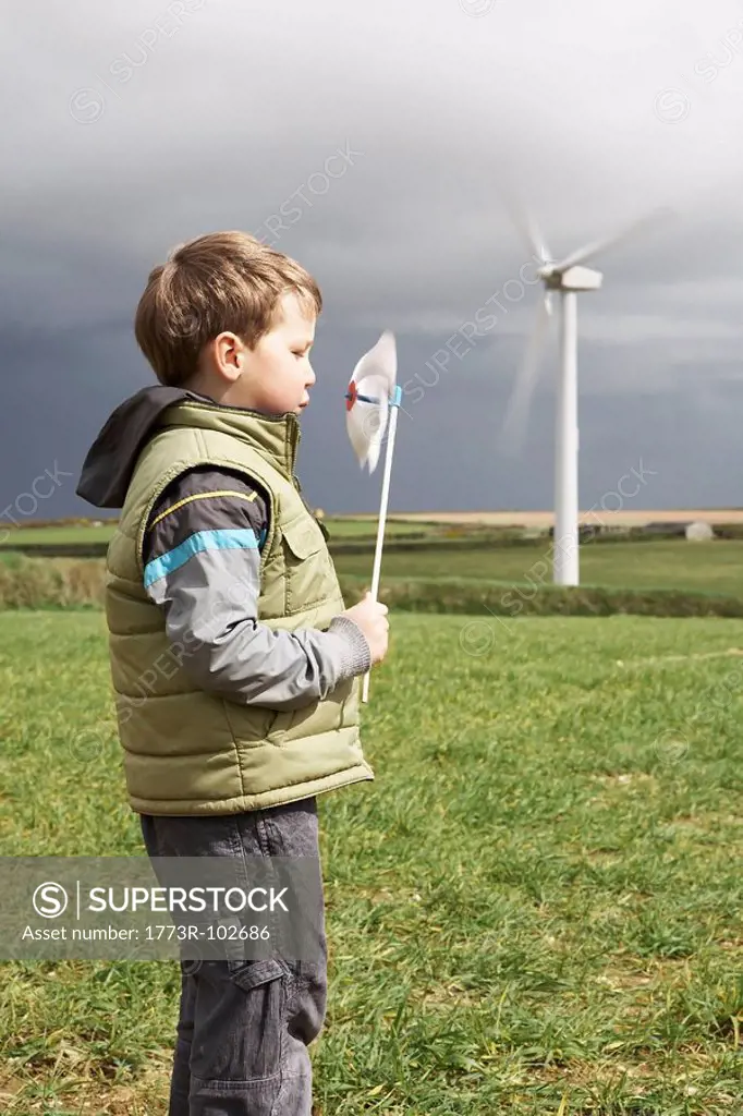 Boy blowing windmill on a wind farm