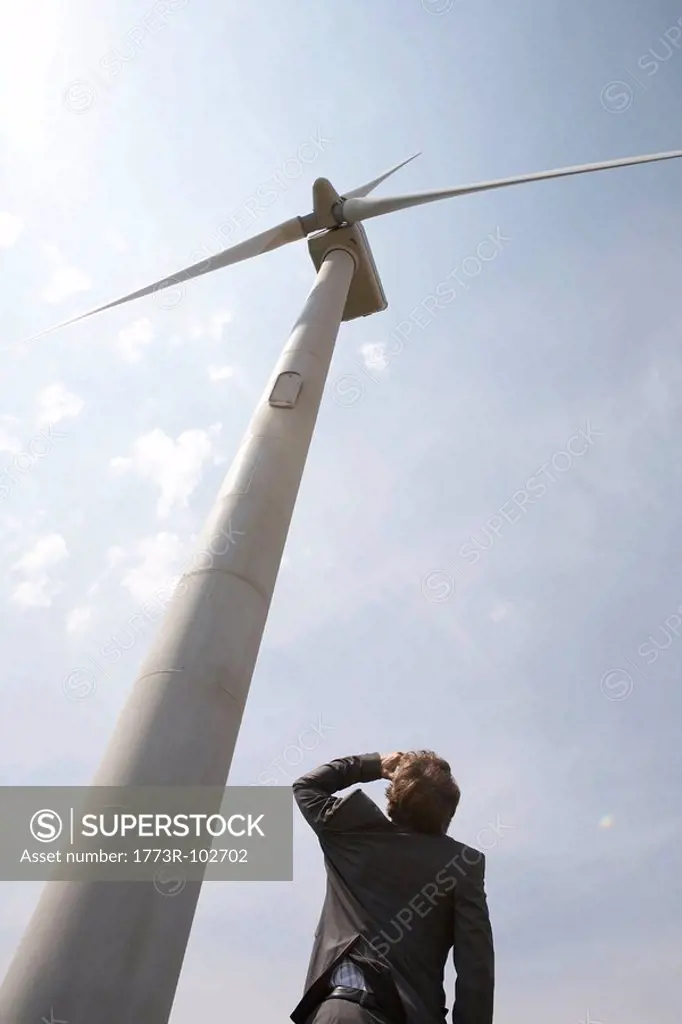 Businessman looking up at wind turbine