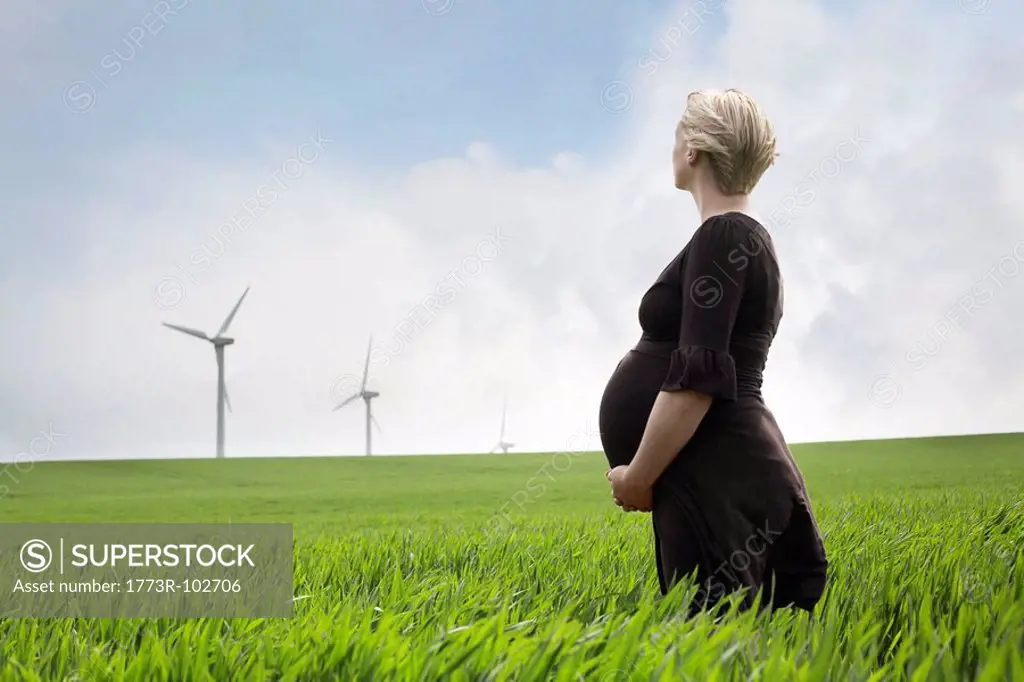 Pregnant woman looking at wind turbines