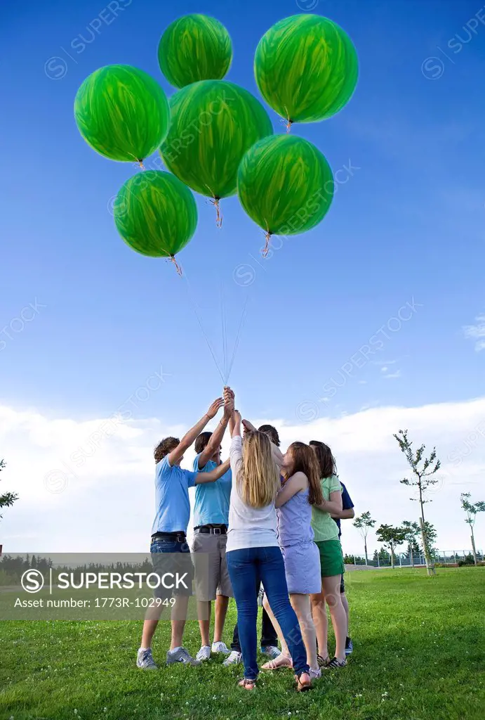 Teenagers holding helium green balloons