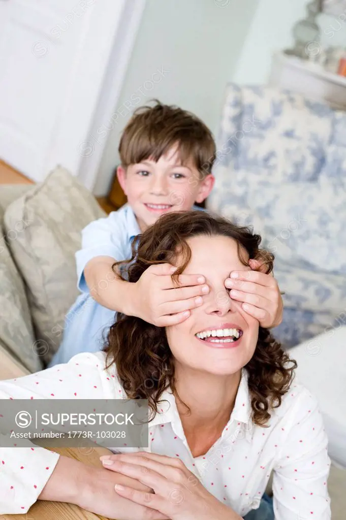 Boy holding the eyes of his mum closed