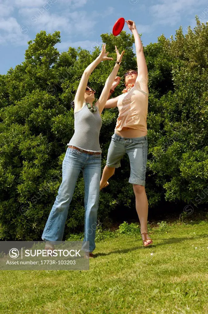 Two women jumping to catch a frisbee