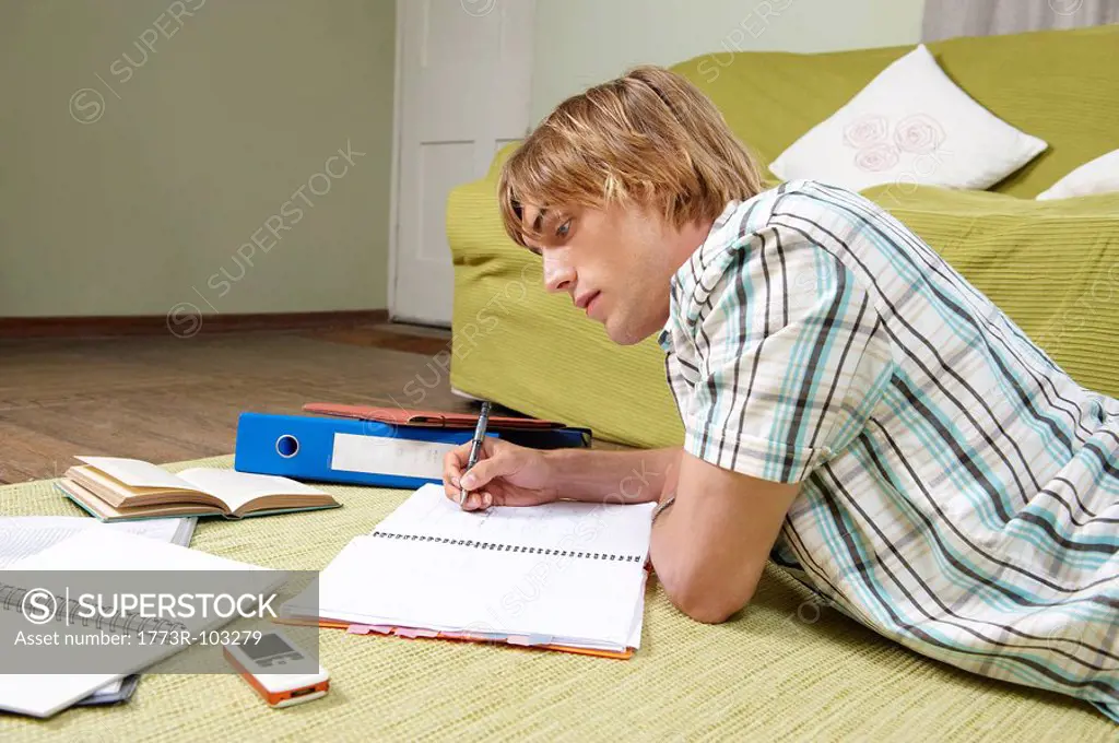 Young man doing home work on rug
