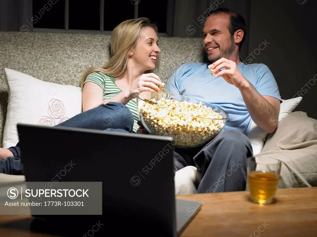 Young couple sharing popcorn on couch