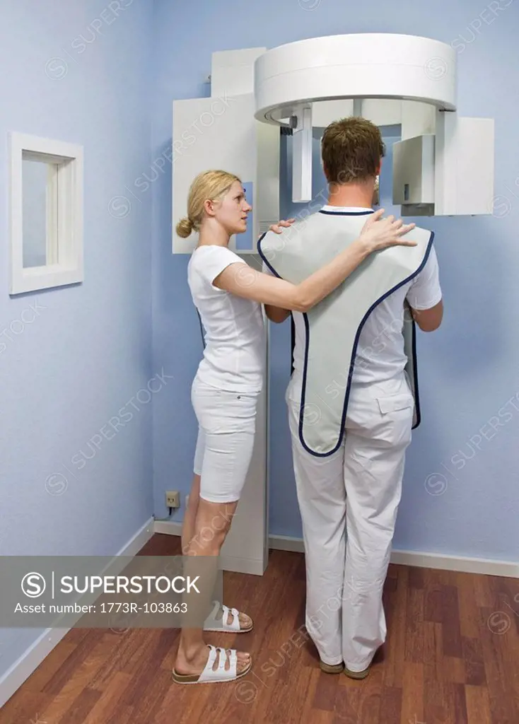 Assistant helps patient with x_ray