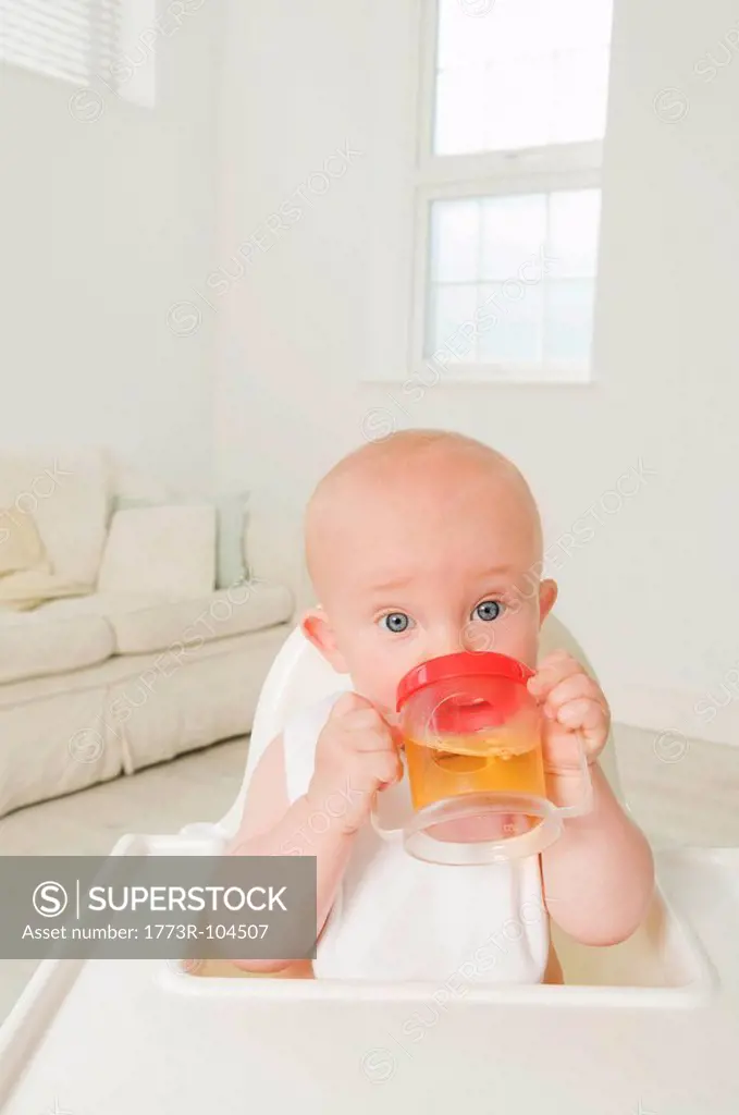 A portrait of a baby drinking juice.