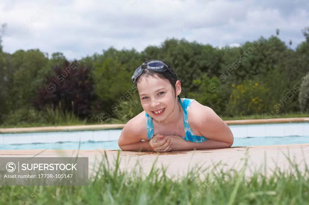 Young girl smiling by swimming pool