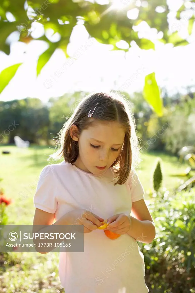 Young girl outside eating fruit