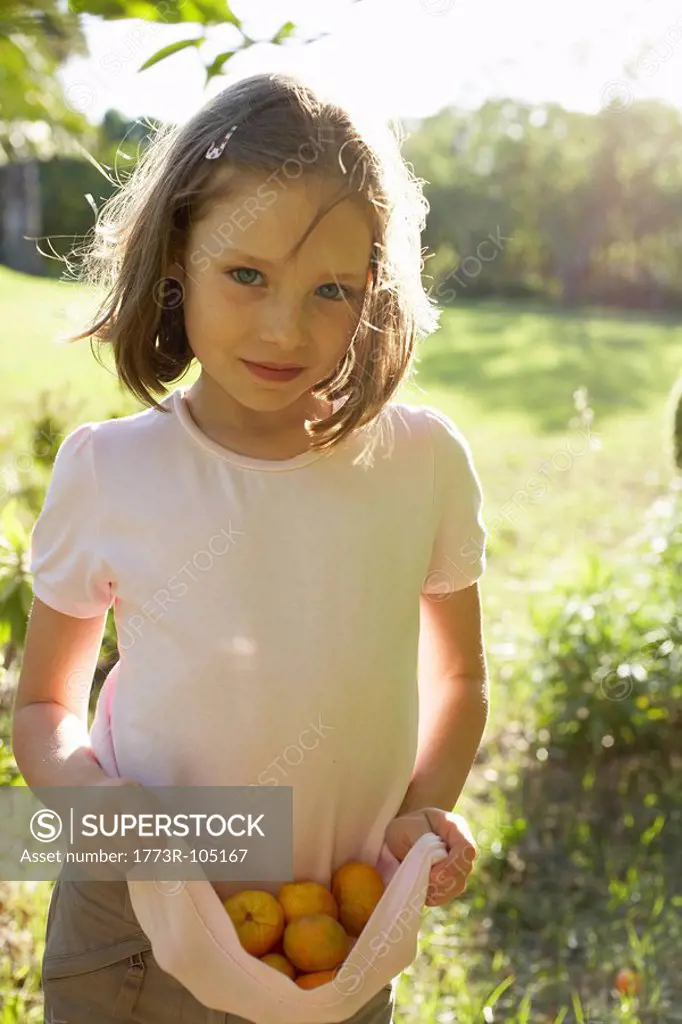 Young girl outside collecting fruit