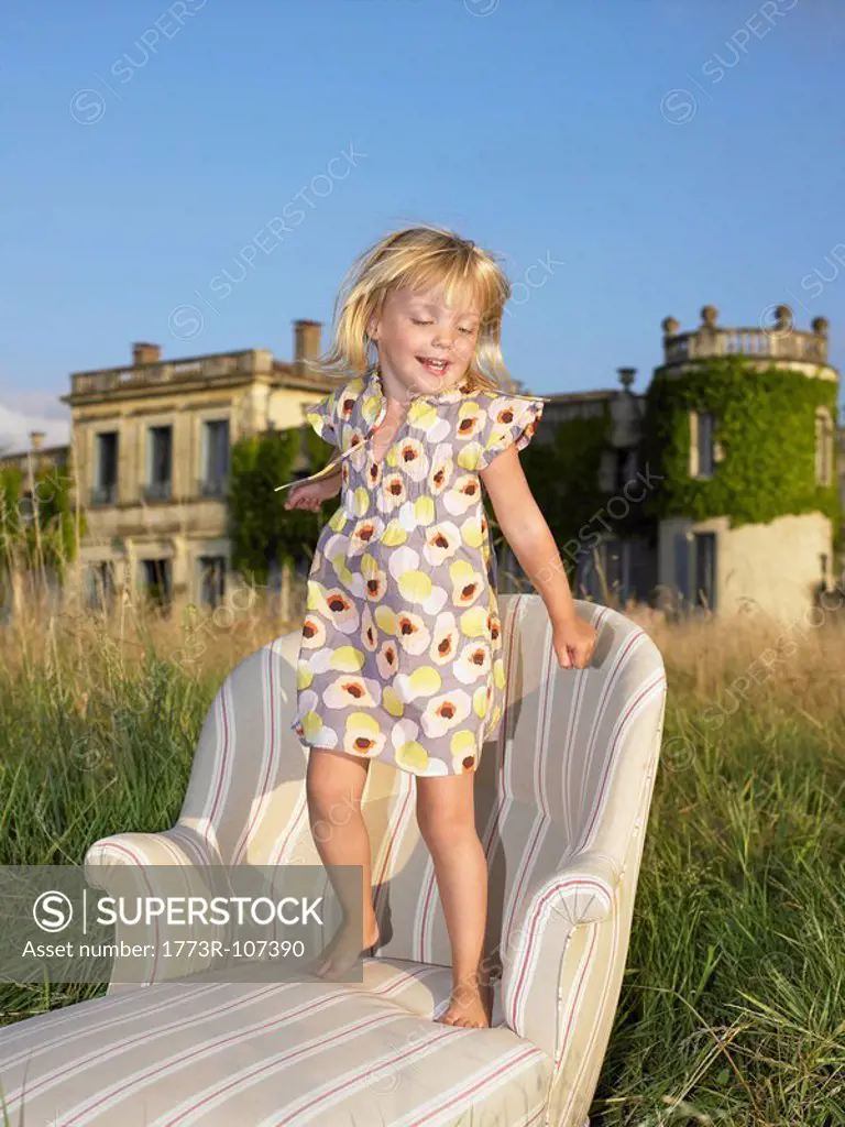 Girl jumping on sofa in a field