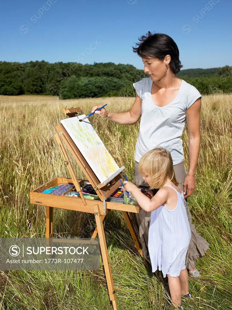 Mother and daughter painting in a field