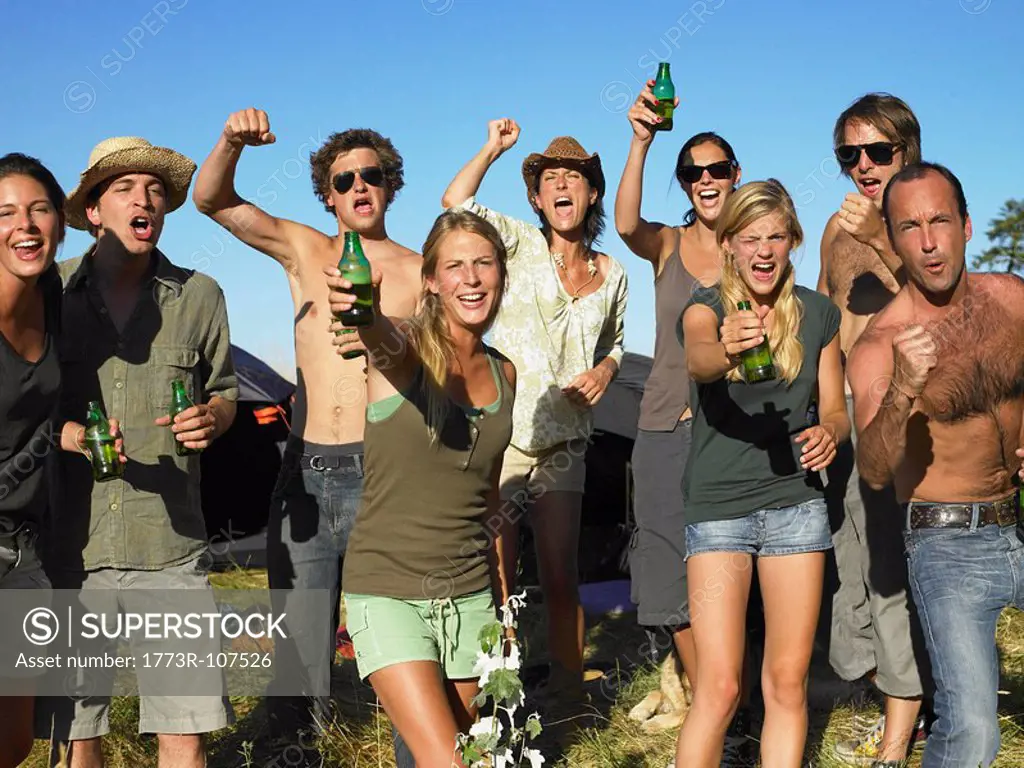 People in a field, raising their beer