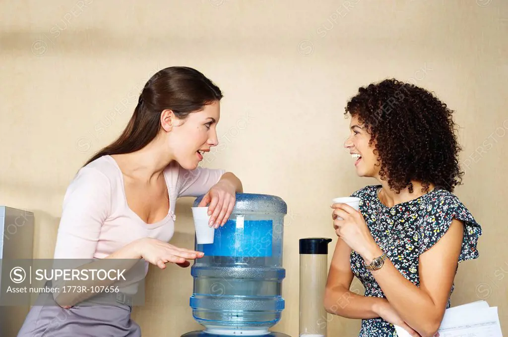 Two women are chatting by water cooler