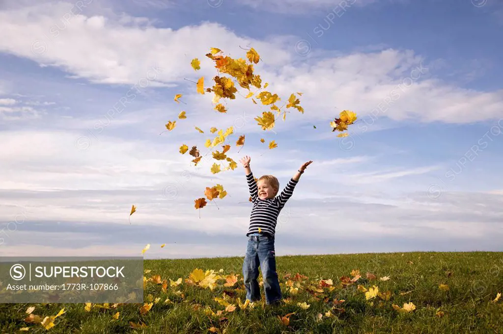 Boy throwing leaves into the air
