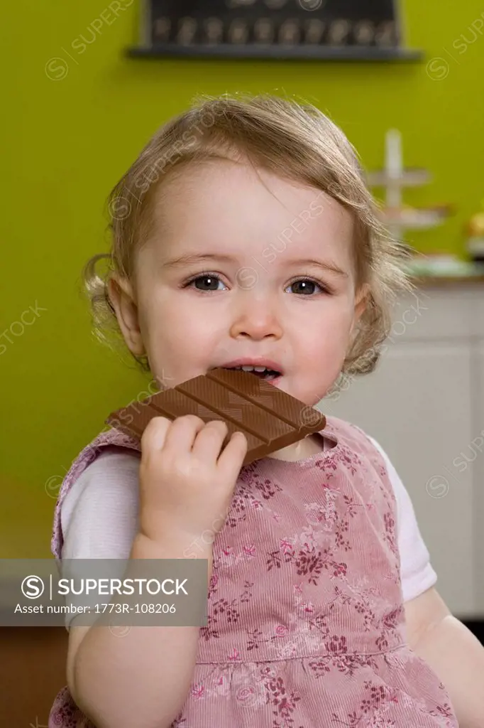 Young girl biting into chocolate bar