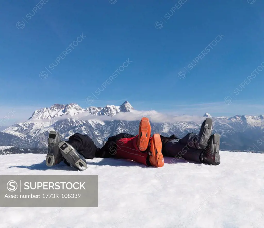 3 men lying in snow on top of mountain