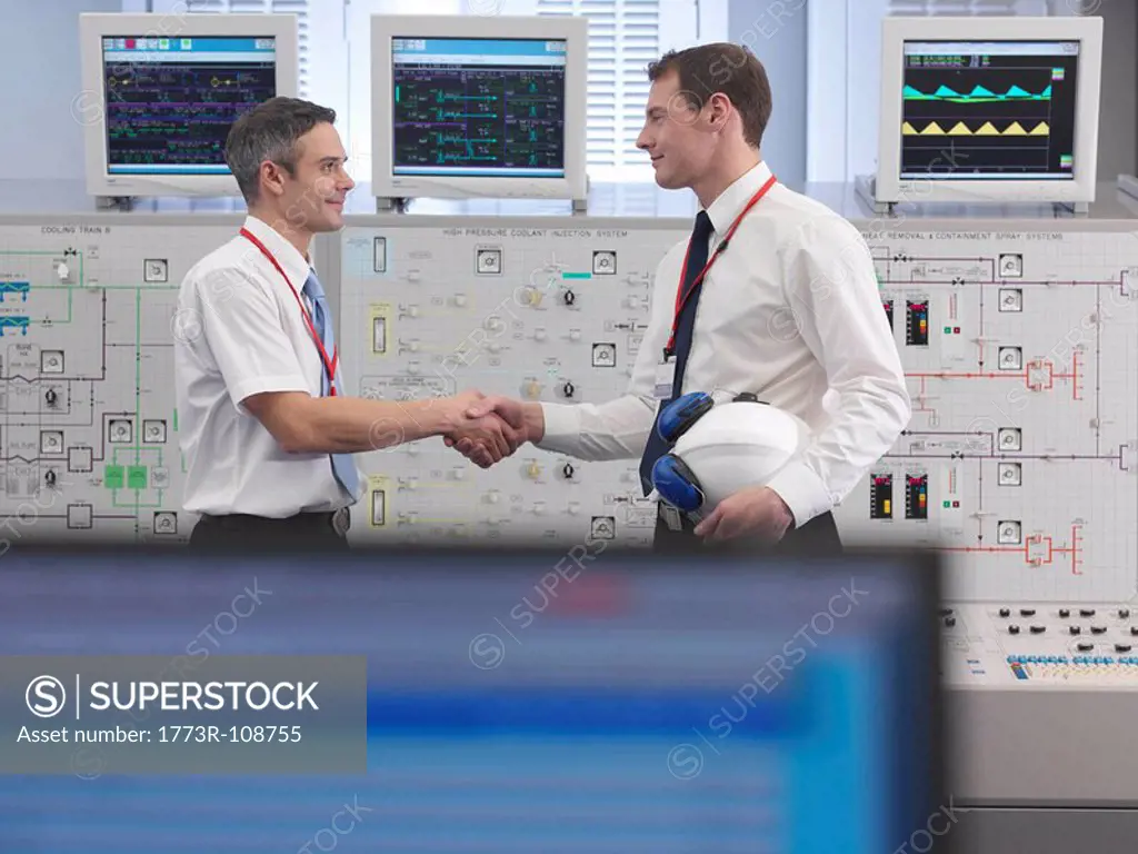 Operators shaking hands in control room
