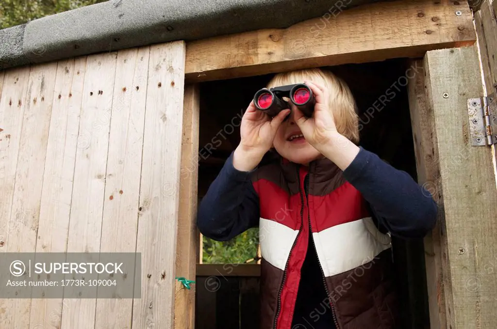Young boy in treehouse with binoculars