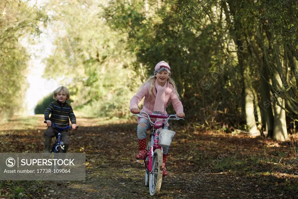 Boy and girl riding bikes in countryside