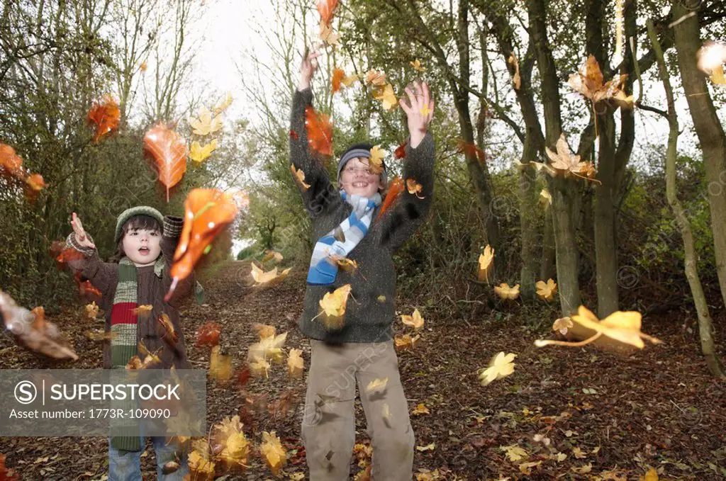 Boys throwing autumn leaves