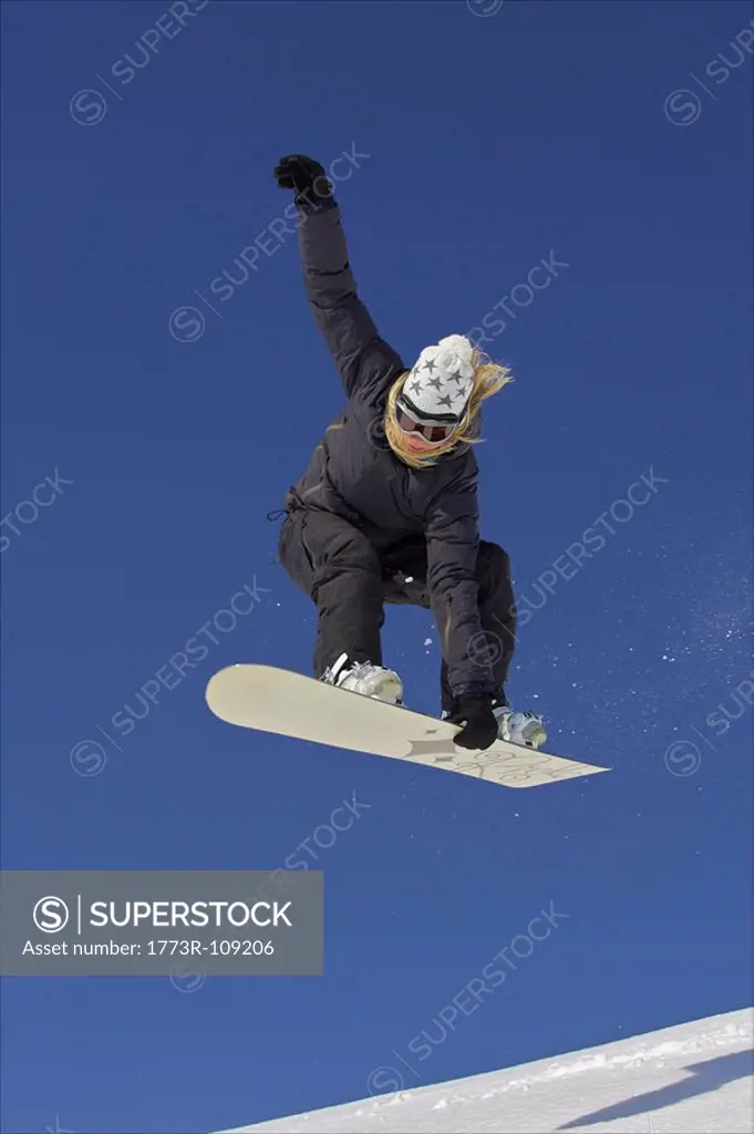 Female snowboarder jumping with a grab