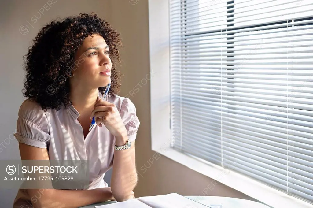 Young woman with pen poised, thinking