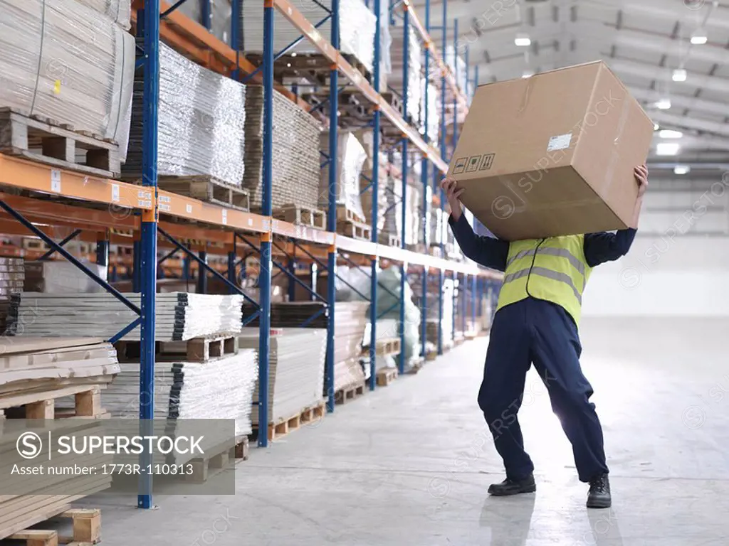 Worker Struggling With Box In Warehouse