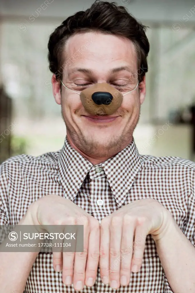 man with toy dog nose smiling