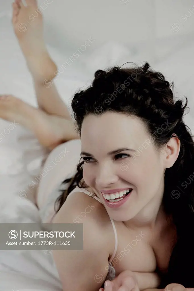 Woman laying on bed, laughing.