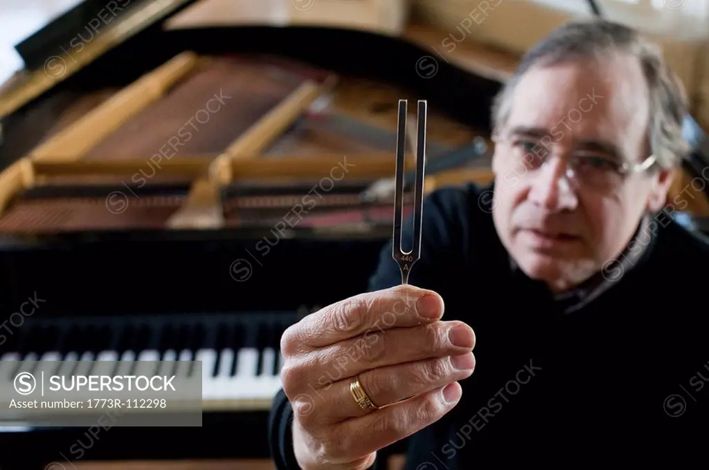 Piano tuner holding tuning fork