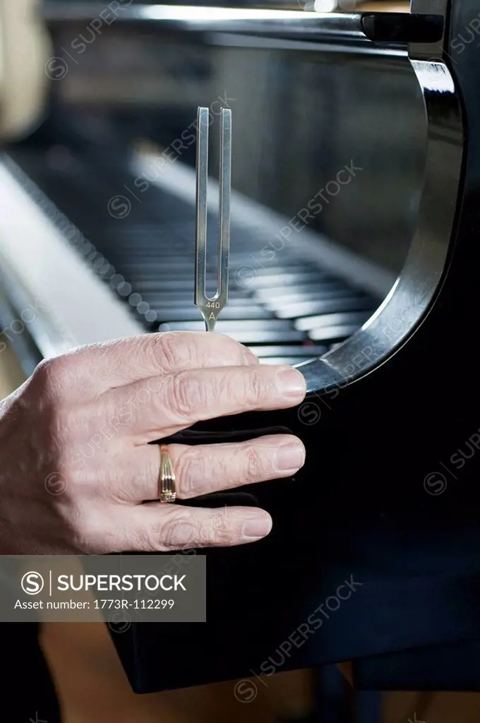 Tuning fork held on grand piano