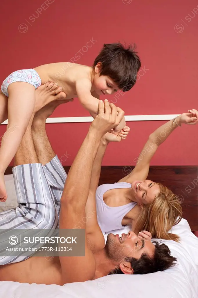 couple playing in bed with boy